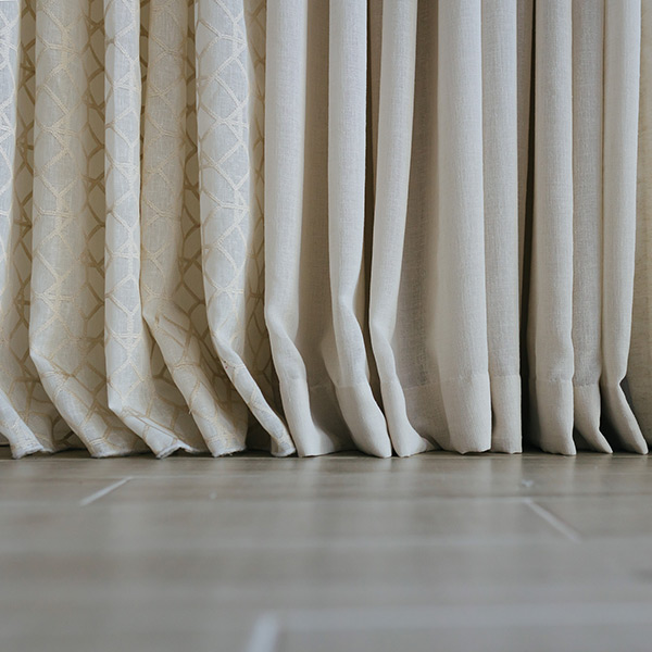 Close-up of beige floor-length curtains with a subtle pattern