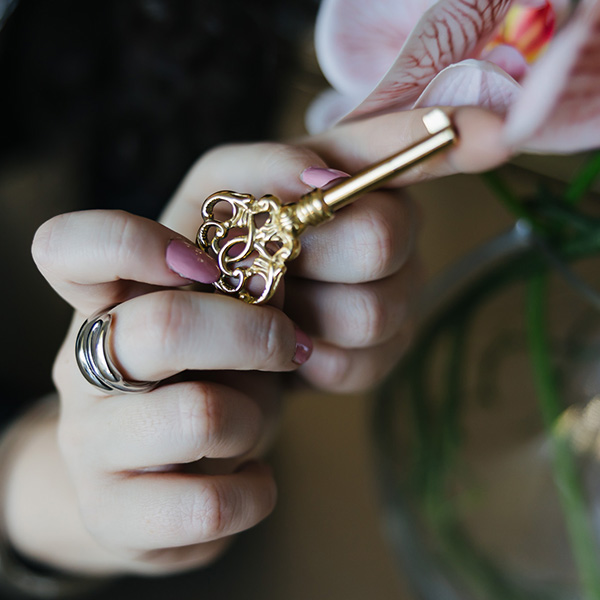 Close-up of hands holding an ornate gold key with a floral design